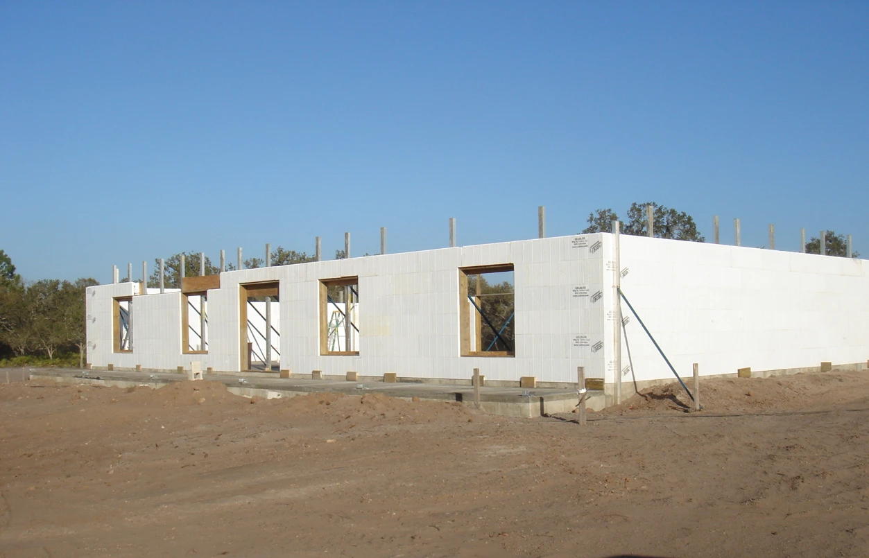 Long commercial ICF building nearing wall completion, with rebar dowels extending from the top of the white insulated concrete form walls awaiting the next concrete pour.