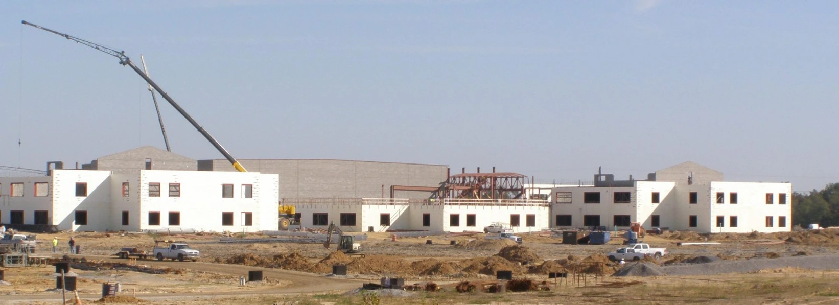 Panoramic view of a large Kentucky school building under construction with multiple wings of white CelBlox insulated concrete form walls, a tower crane, and an active commercial construction site.
