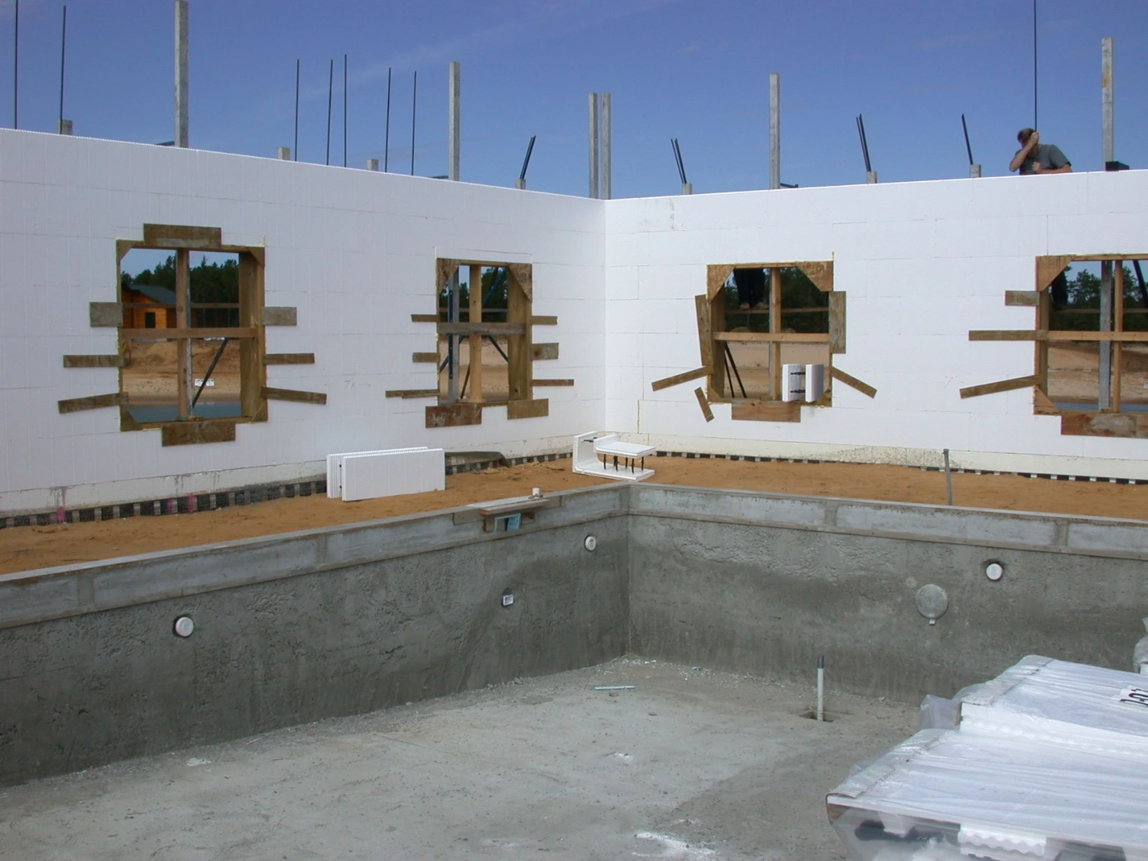 Below-grade ICF pool structure for a commercial facility, with white insulated concrete form walls framed for windows above a poured concrete pool basin.