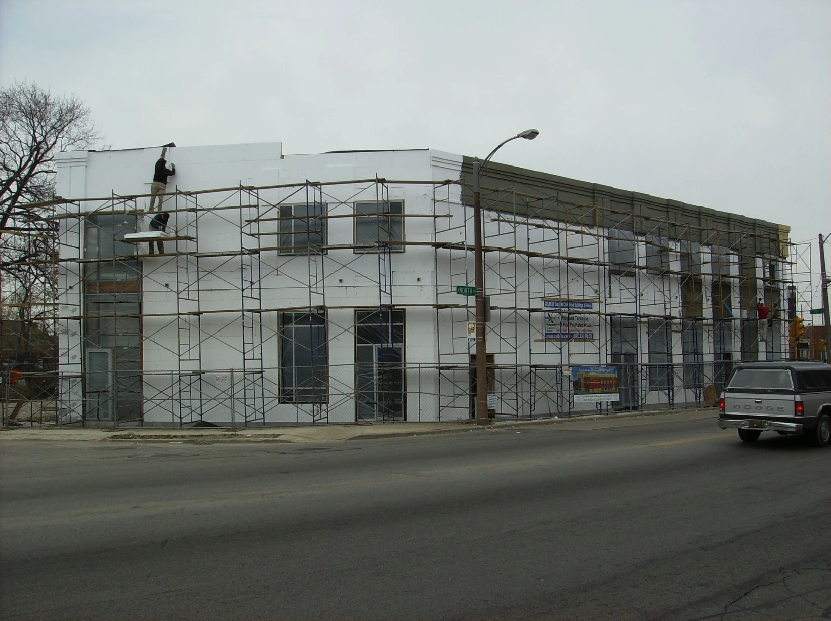 Commercial ICF building on a downtown street corner, wrapped in scaffolding with white insulated concrete form walls visible through the scaffold framework.