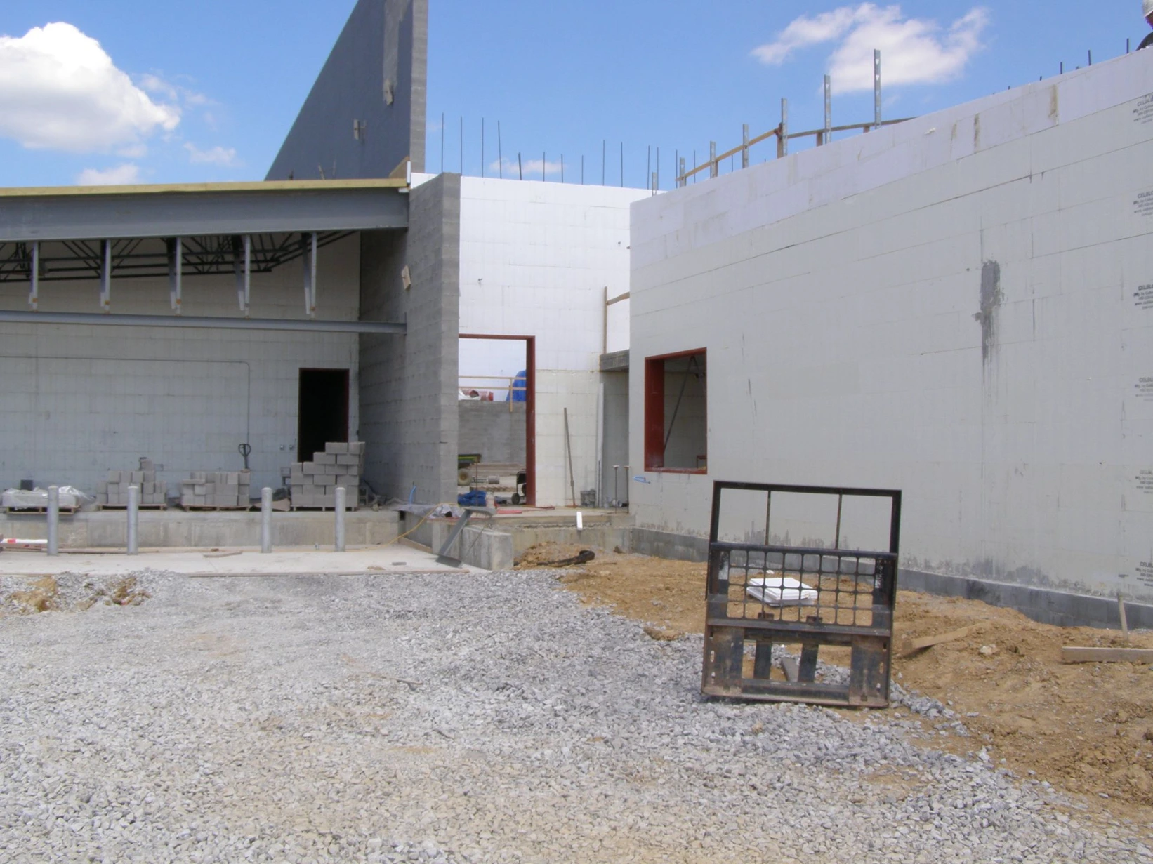 Commercial ICF building with a steel canopy overhang and white insulated concrete form walls forming a loading dock entrance, red door frames, and a gravel lot.