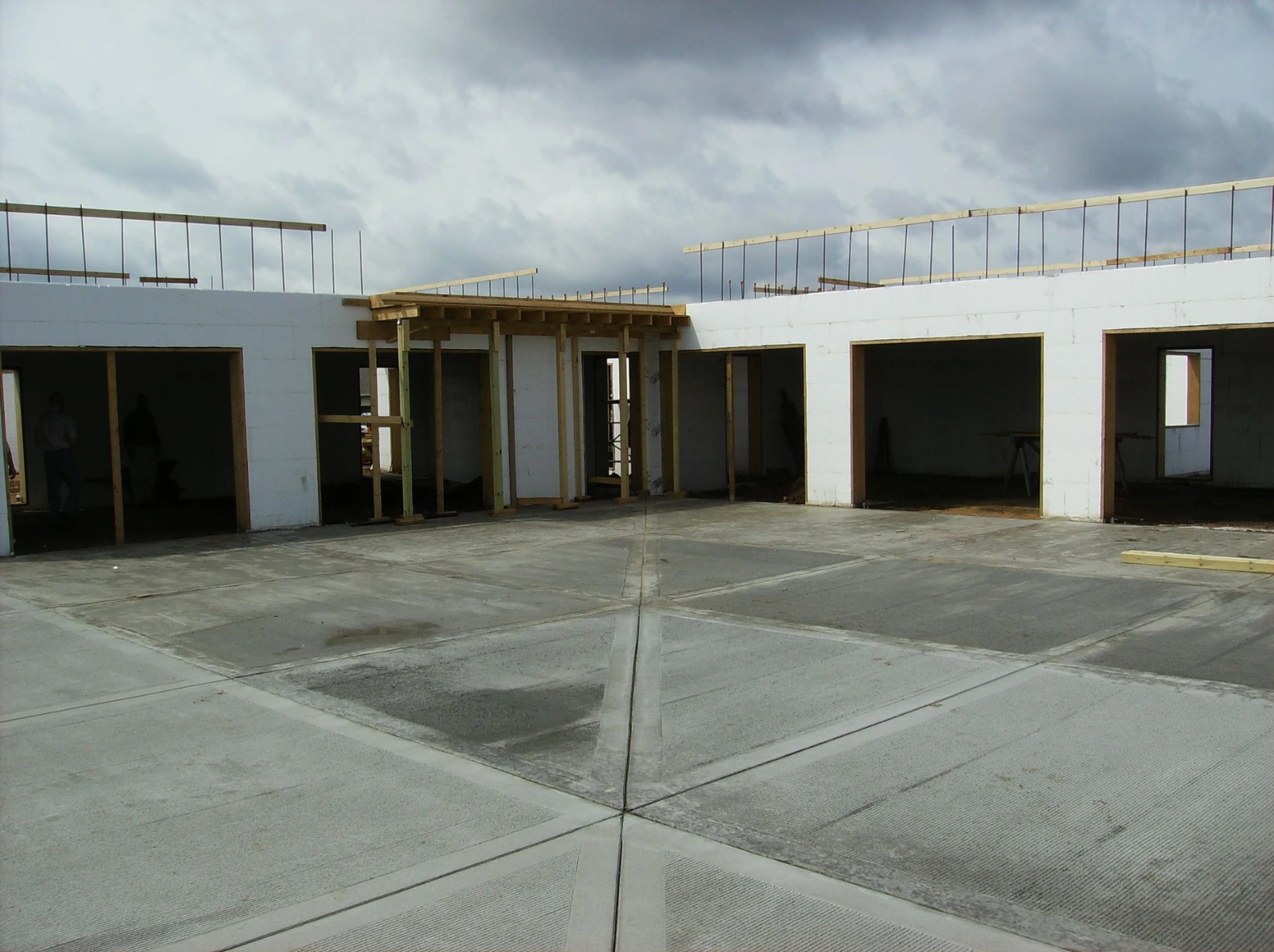 Courtyard view of a commercial ICF building with white insulated concrete form walls, second-story wood framing, and multiple door and window openings.
